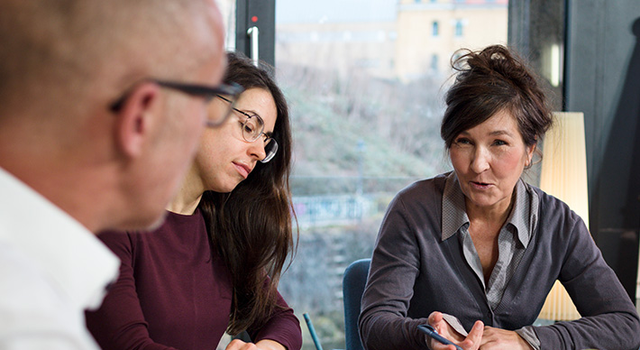 Zwei Frauen und ein Mann am Tisch sitzend im Gespr�ch