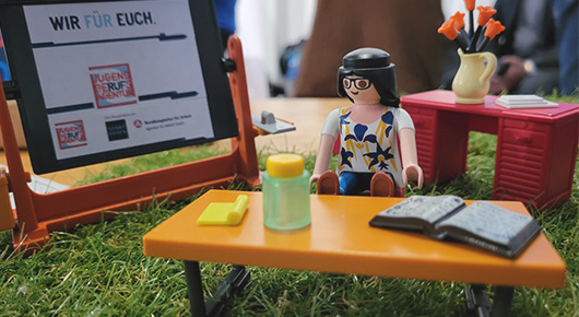 Lego-Modell mit Figur an Schreibtisch sowie Wandtafel mit Logo der JBA Essen und Text "Wir f�r euch"
