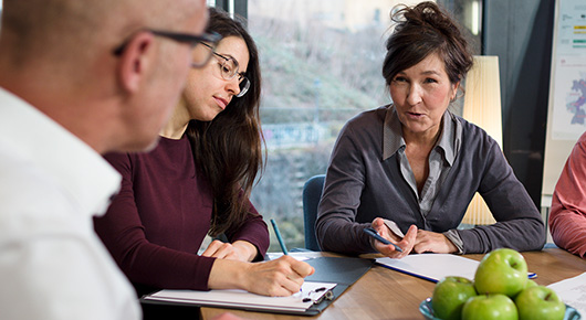 Drei Personen am Tisch im Gespräch Drei Personen am Tisch im Gespräch